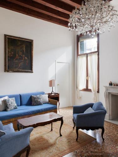 a living room with blue couches and a chandelier at Palazzo Contarini Della Porta Di Ferro in Venice