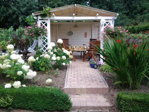 a white gazebo with a table and chairs in a garden at Vakantie Appartementen Engelen in Stevensweert