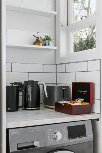 a kitchen counter with two coffee pots and a microwave at Garden Oasis - 5min walk to CBD in Gisborne