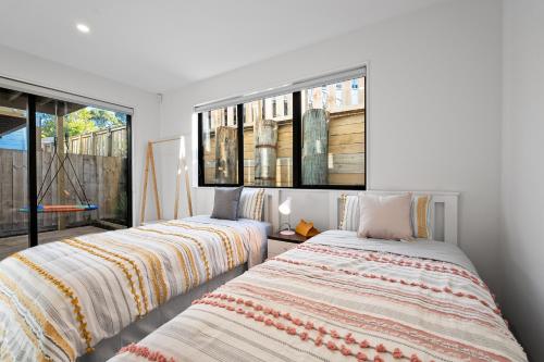 two beds in a room with two windows at Luxury 4 BR Retreat 4 bath with 3 Master Suites and Kids' Playroom in Auckland