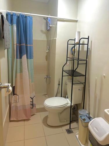 a bathroom with a toilet and a shower at Cozy 2BR Unit in VINE Residences, Quezon City in Manila