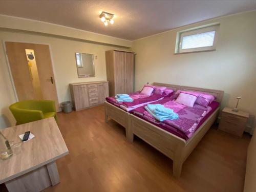 a bedroom with a bed with purple sheets and a table at Pension und Ferienwohnung Kristen Am Denkmal Süptitzer Höhen in Zietenhof