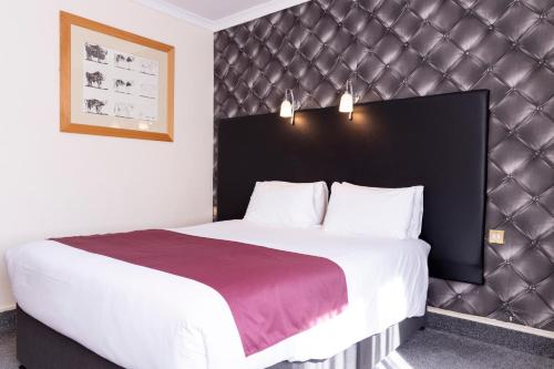 a bedroom with a large bed with a black headboard at Roebuck by Greene King Inns in Forest Row