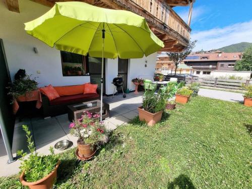 a patio with a green umbrella and some plants at Appartement Berghof "Dettis Place" in Gerlos