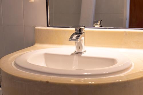 a bathroom sink with a faucet in front of a mirror at Roebuck by Greene King Inns in Forest Row