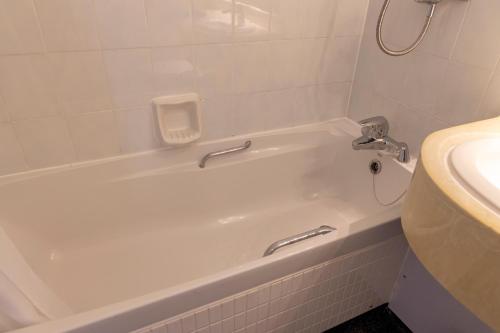a white bath tub in a bathroom with a sink at Roebuck by Greene King Inns in Forest Row