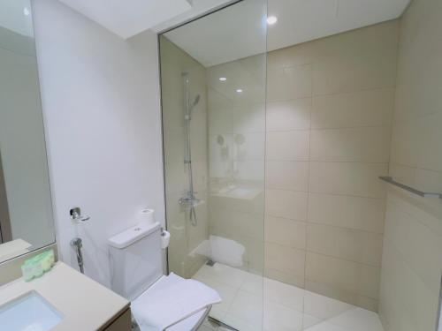 a white bathroom with a shower and a toilet at Cosy Studio in Yas Island, Abu Dhabi in Abu Dhabi
