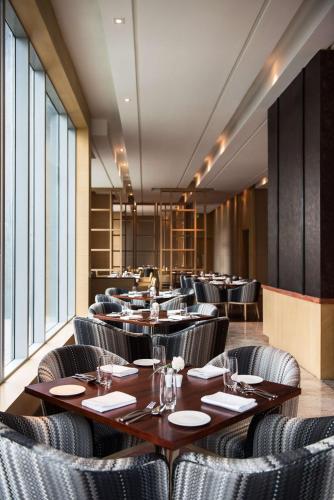 a dining room with tables and chairs and windows at Hyatt Regency Lucknow Gomti Nagar in Lucknow