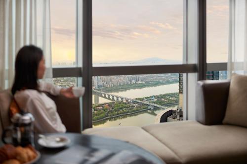 a woman holding a cup of coffee in front of a window at Grand Hyatt Changsha-Close to Helong Sports Center in Changsha