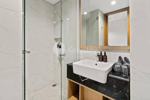 Un baño blanco con lavabo y ducha. en Calira by Kozystay - Nusa Dua, en Nusa Dua