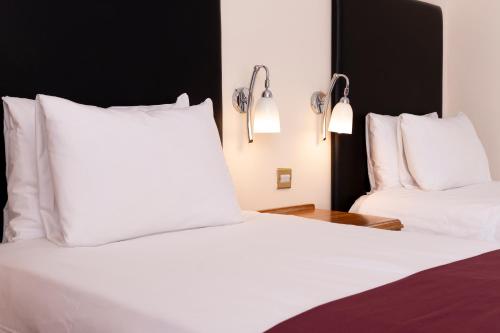 two beds in a hotel room with white pillows at Roebuck by Greene King Inns in Forest Row