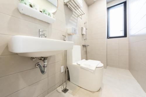 a white bathroom with a sink and a toilet at 暮夏包棟民宿4-16人 -新成屋-電梯-烤肉-預訂完成後務必聯繫再度確認 in Tainan