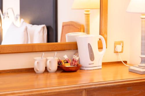 a coffee maker sitting on a wooden table in front of a mirror at Roebuck by Greene King Inns in Forest Row