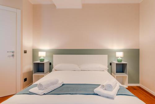 Un dormitorio con una gran cama blanca con toallas. en Casa Mocambo by Toh Solution, en Turín