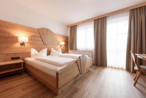 a bedroom with a large bed with a wooden wall at Landhaus Pfurtscheller in Neustift im Stubaital