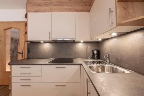 a kitchen with white cabinets and a sink at Landhaus Pfurtscheller in Neustift im Stubaital