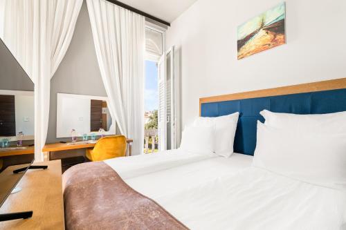 a bedroom with a bed and a desk and a window at Hotel Dua Residence in Poreč