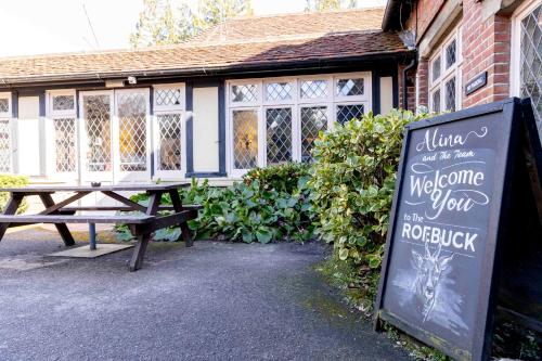 a picnic table and a sign in front of a building at Roebuck by Greene King Inns in Forest Row