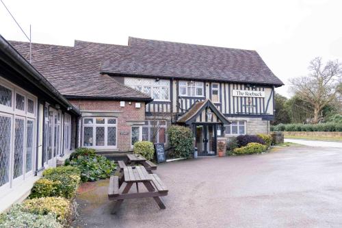 a building with picnic benches in front of it at Roebuck by Greene King Inns in Forest Row