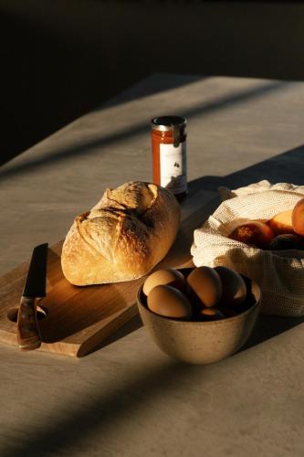 a loaf of bread and a bowl of eggs on a cutting board at Stone - Rare Earth Retreats in McLaren Vale