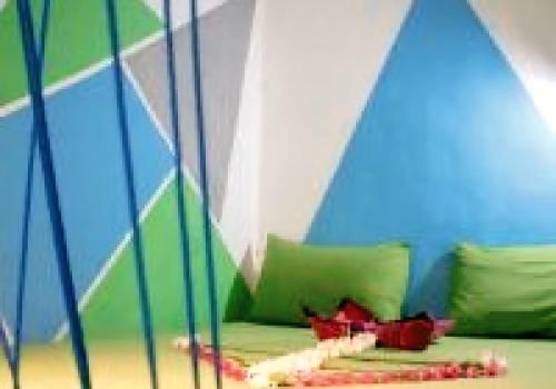 a room with a couch with green and blue walls at Jati Village, Party Hostel and Bungalows in Gili Trawangan