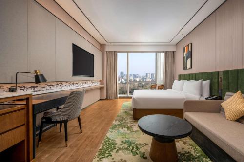 a hotel room with a bed and a desk and a couch at Hilton Garden Inn Suzhou Kunshan in Suzhou