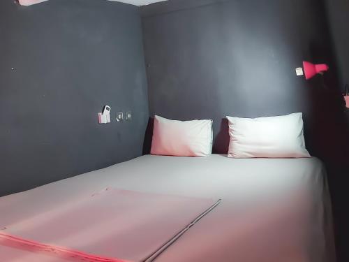 a bed with white sheets and pink pillows in a room at Jati Village, Party Hostel and Bungalows in Gili Trawangan
