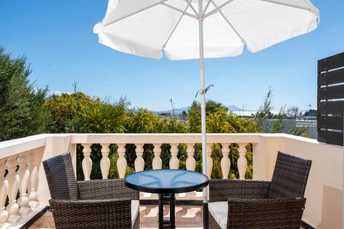 a table and chairs on a balcony with an umbrella at Melathron II-Sea View apartment -Adults only Plus 16 in Kefalos