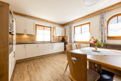 a kitchen with white cabinets and a table and chairs at Landhaus Pfurtscheller in Neustift im Stubaital