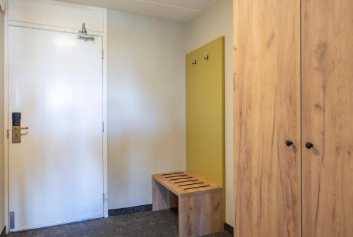a room with a wooden bench next to a closet at Fletcher Hotel Jan van Scorel in Schoorl