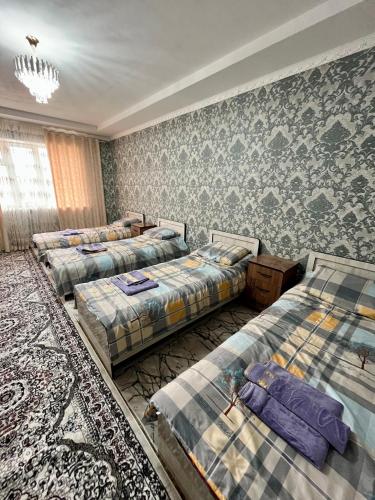 a room with four beds and a chandelier at October Guesthouse in Jalal-Abad