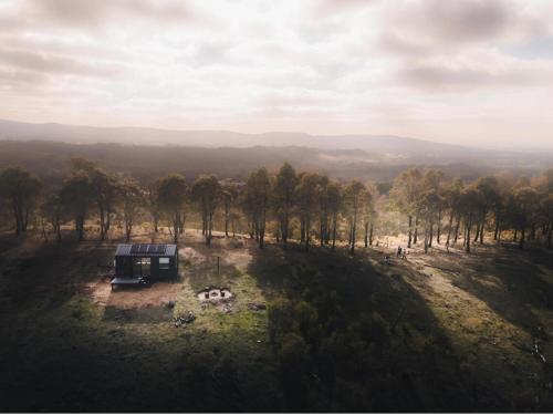 Una vista aérea de una casa en una colina con árboles. en Designer Off-Grid Cabin Retreat by Famous Startup - Frankie, en Warrenmang