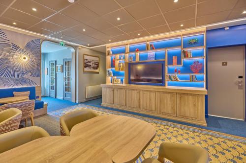 a waiting room with tables and a flat screen tv at Hôtel Le Jersey in Saint Malo