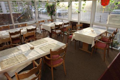 un restaurante con mesas y sillas blancas y ventanas en Hotel Happy, en Bad Bramstedt