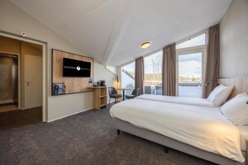 a hotel room with a bed and a flat screen tv at Fletcher Hotel Jan van Scorel in Schoorl