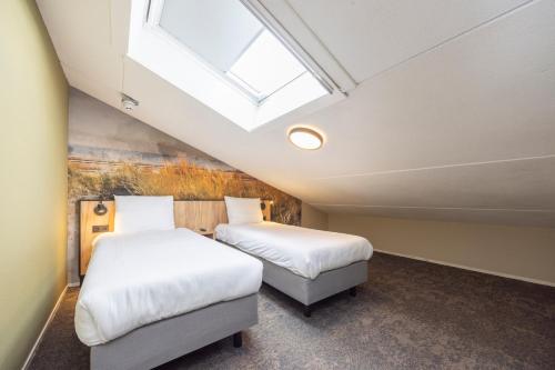 two beds in a room with a skylight at Fletcher Hotel Jan van Scorel in Schoorl