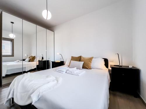 ein weißes Schlafzimmer mit einem großen weißen Bett und Spiegeln in der Unterkunft Francoforte 10 in Olbia