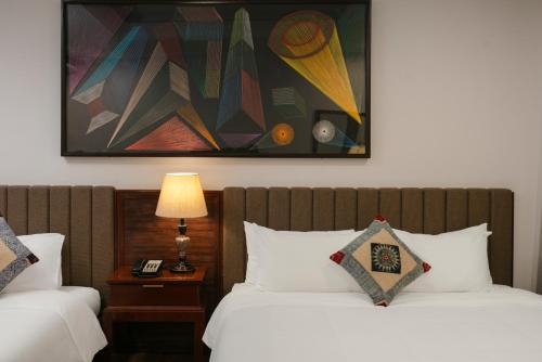 two beds in a hotel room with a painting on the wall at Bamboo Sapa Hotel in Sa Pa