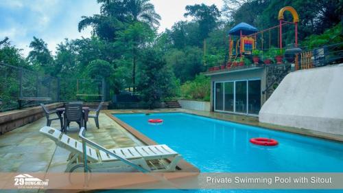 a swimming pool with two chairs and a playground at Lilly Valley Villa In Lonavala in Lonavala