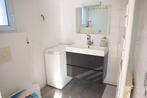 une salle de bain blanche avec un lavabo et un miroir dans l'établissement Le Havre de Paix, à Bréziers