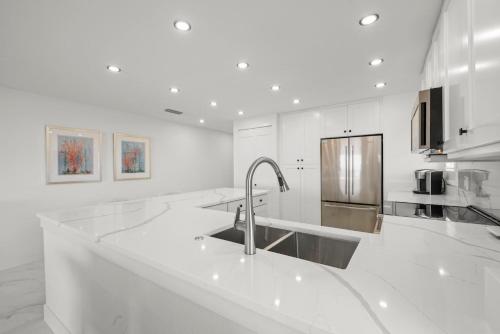 Una cocina blanca con fregadero y refrigerador. en Sanddollar #B301, en Sanibel