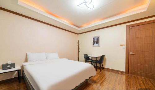 a bedroom with a bed and a table and a door at Donghae Gloria Hotel in Donghae