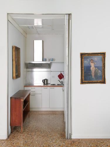 a kitchen with white cabinets and a painting on the wall at Palazzo Contarini Della Porta Di Ferro in Venice
