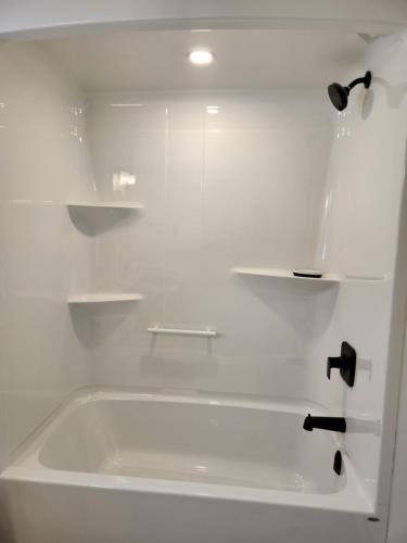 a white bath tub with shelves in a bathroom at Naya Kozy in St. John's
