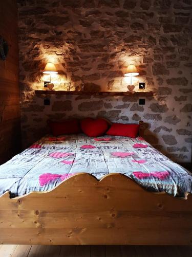 une chambre avec un lit avec deux oreillers rouges dans l'établissement GITE LE CALOU AVEC JACUZZI situé à St Laurent-en-Grandvaux - du samedi au samedi uniquement, à Saint-Laurent-en-Grandvaux