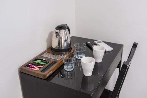 una mesa negra con gafas y una cafetera. en Wine & Four - Chambre Agréable sur les Allées, en Toulouse