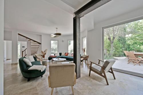 un salon avec un canapé vert et des chaises dans l'établissement Villa avec piscine - 5 min d'Avignon, aux Angles (Gard)