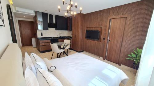 a bedroom with a white bed and a kitchen at Jasmin Ain Zaghouane in El Aouina Station