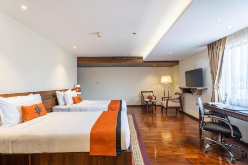 a hotel room with two beds and a desk at Ramada by Wyndham Kathmandu Dhumbarahi in Kathmandu