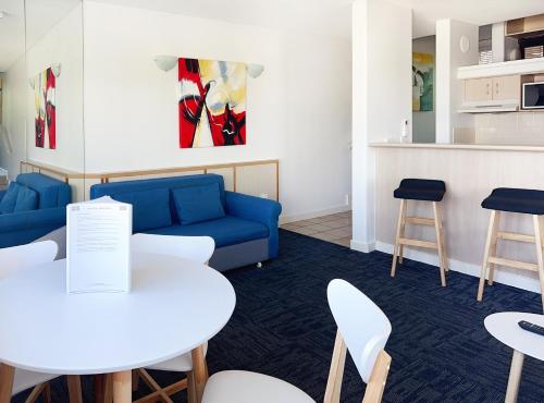 a living room with a couch and tables and chairs at Tiki Hotel Apartments Surfers Paradise in Gold Coast